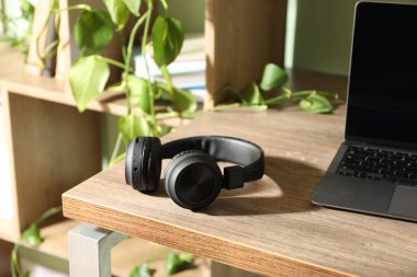 Laptop ve kablosuz kulaklıklar ahşap masa içinde.