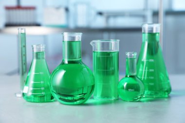 İçerideki ışık masasında yeşil sıvı bulunan farklı bir laboratuar cam.