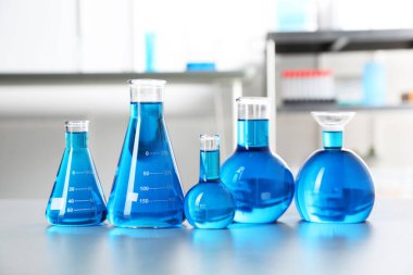 İçerideki masada açık mavi sıvı bulunan farklı bir laboratuvar camı.