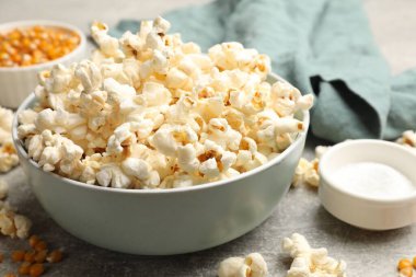 Açık gri masada patlamış mısır ve mısır taneleri, yakın plan.