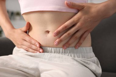 Evdeki kanepede göbekli bir kadın, yakın plan.