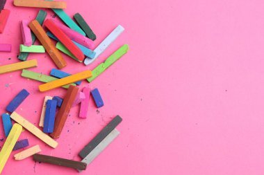 Pembe arka planda bir sürü renkli tebeşir renginde boya var. Metin için boşluk