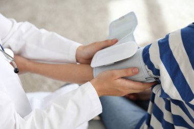 Doktor, kadının kalp atış hızını ve kan basıncını kapalı mekanda sphygmomanometre ile ölçüyor.