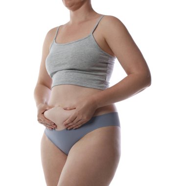 Yağ aldırma. İç çamaşırlı kadın beyaz arka planda karnına dokunuyor, yakın plan.