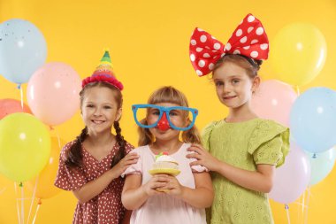 Doğum günü kutlaması. Turuncu arka planda balonları olan çocuklar.