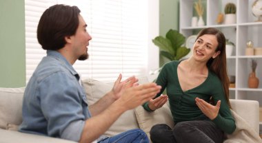 Kadın ve erkek evdeki kanepede konuşuyor.