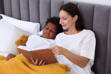 Anne evdeki oğluna masal okuyor.