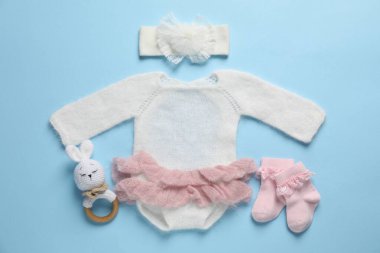 Açık mavi arka planda şık bebek kıyafetleri ve aksesuarları.