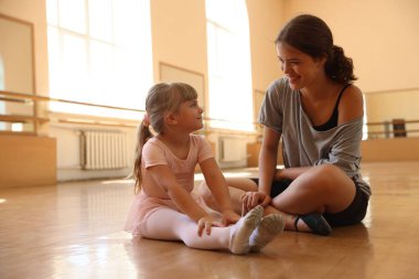 Dans sınıfında küçük bir kızla çalışırken mutlu bir bale öğretmeni.