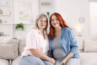 Hamile kadın ve annesi evdeki kanepede.