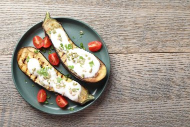 Kabak çekirdekli ızgara patlıcan, domates ve yoğurt dilimleri, ahşap masa, üst manzara. Metin için boşluk