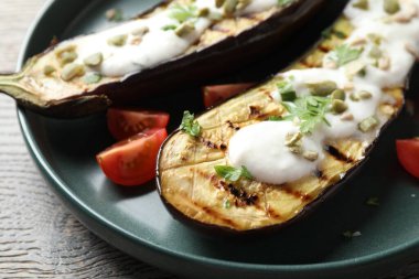 Patlıcan dilimleri, balkabağı çekirdekleri, domates ve yoğurt, ahşap masa, yakın plan.