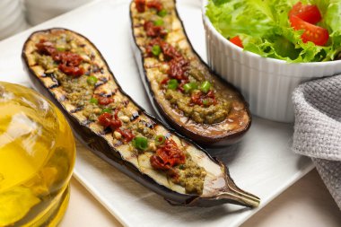 Izgara patlıcan dilimleri, güneşte kurutulmuş domates, pesto ve salata, yakın plan.