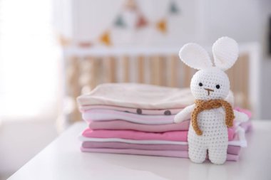 Temiz bebek kıyafetleri ve aksesuar yığını beyaz masa içinde, yakın plan.