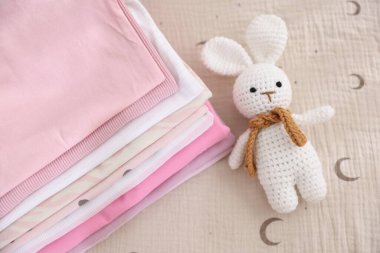 Temiz bebek kıyafetleri ve çarşaflara aksesuar yığını.