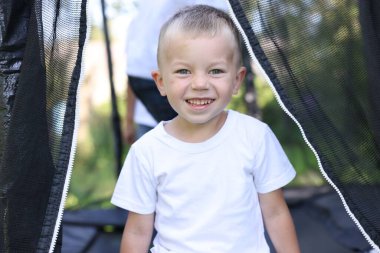 Dışarıdaki siyah trambolinde mutlu küçük bir çocuğun portresi.