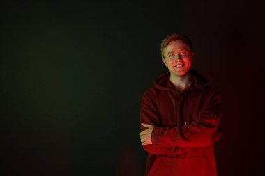 Siyah arka plana karşı kollarını çapraz bağlayan kapüşonlu adam portresi. Metin için boşluk