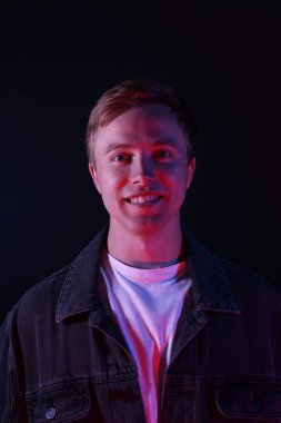 Siyah arka planda neon ışıklarda gülümseyen bir adamın portresi