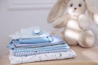 Temiz bebek kıyafetleri ve aksesuarlar ahşap masa içinde, yakın plan.