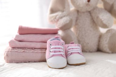 Temiz bebek kıyafetleri ve çarşafların üzerindeki ayakkabılar, yakın plan.