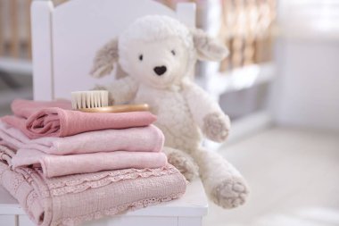 İçerideki küçük koltukta temiz bebek kıyafetleri ve aksesuarlar yığını, yakın plan. Metin için boşluk