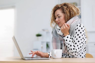 Klima. Ofisteki işyerinde eşarplı kadın soğuk hava nedeniyle acı çekiyor.