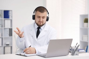 Kulaklıklı doktor içeride bilgisayarla online danışmanlık yapıyor.