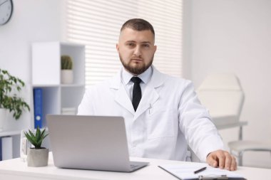 Klinikte dizüstü bilgisayarla çalışan bir doktor. Online tıbbi danışmanlık
