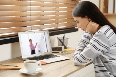 E-öğrenme konsepti. Öğrenci masadaki dizüstü bilgisayarla öğretmenle görüntülü konuşma yapıyor