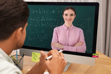 E-öğrenme konsepti. Öğrenci masadaki bilgisayar aracılığıyla öğretmenle görüntülü konuşma yapıyor.