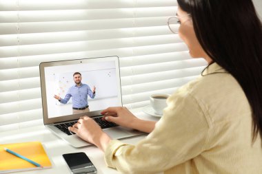 E-öğrenme konsepti. Öğrenci masadaki dizüstü bilgisayarla öğretmenle görüntülü konuşma yapıyor