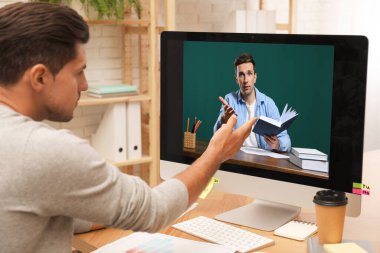 E-öğrenme konsepti. Öğrenci masadaki bilgisayar aracılığıyla öğretmenle çevrimiçi görüntülü sohbet ediyor