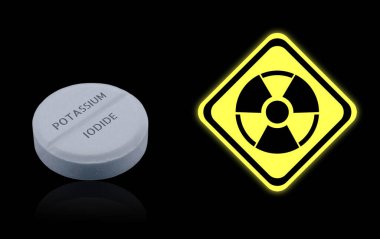 Siyah arka planda potasyum iyodür hapı ve uyarı işareti. Radyoaktif kirlenme sırasında iyot tüketimi