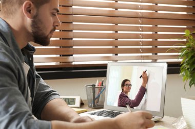 E-öğrenme konsepti. Öğrenci masadaki dizüstü bilgisayarla öğretmenle görüntülü konuşma yapıyor