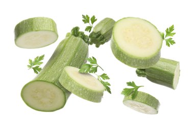 Beyaz arka plana düşen taze kabak ve maydanoz parçaları.