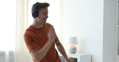 Mutlu adam kulaklıkla müzik dinliyor ve evde dans ediyor.