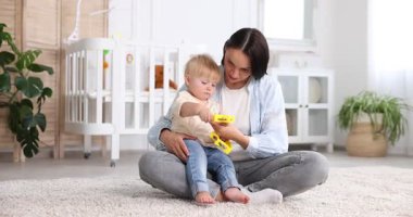 Anne ve küçük tatlı çocuğu bebek odasında oyuncaklarla oynuyorlar.