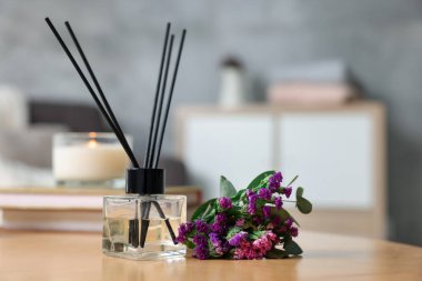 Reed yayıcı ve aromatik çiçekler ahşap masada, yakın plan.