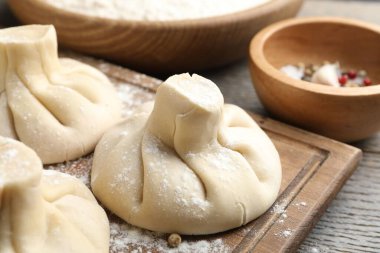 Ahşap masada pişmemiş khinkaliler (hamur tatlısı), yakın plan.