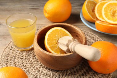 Taze sıkılmış portakal suyu, meyve suyu ve meyve sıkacağı ahşap masada, yakın plan.