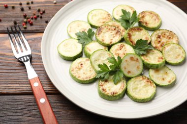 Ahşap masada servis edilen maydanozlu lezzetli kabak dilimleri, yakın plan.