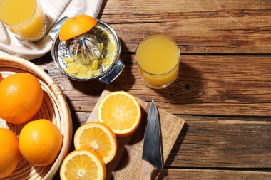 Taze sıkılmış portakal suyu, meyve suyu ve meyve sıkacağı ahşap masada, düz yerde. Metin için boşluk
