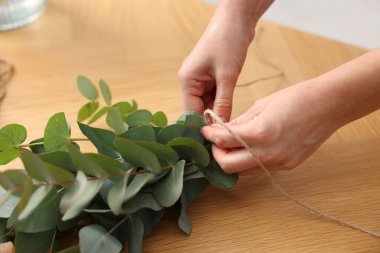 Çiçekçinin ahşap masasında okaliptüs dallarından güzel bir buket yapıyor.