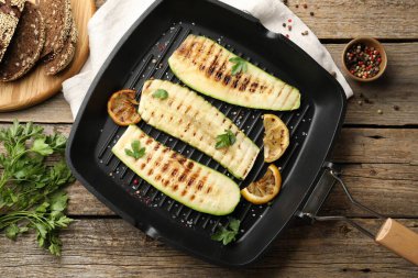 Lezzetli ızgara kabak dilimleri, baharatlar ve tavada limon, ahşap masa, düz yatış.