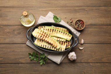 Lezzetli ızgara kabak dilimleri, ahşap masa üzerinde yağ ve baharatlar, düz uzanma