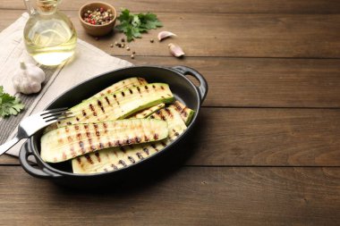 Lezzetli ızgara kabak dilimleri fırında, baharatlar ve maydanozlar ahşap masada, yazı için yer var.