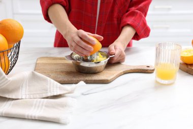 Meyve suyu. İçerideki beyaz mermer masada portakal suyu kullanan kadın, yakın plan.