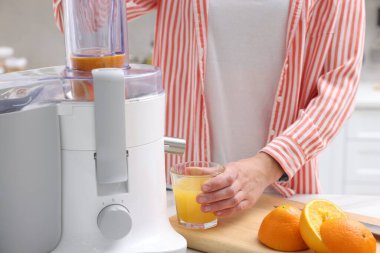 Kadın, modern meyve sıkacağıyla taze portakal suyu yapıyor.