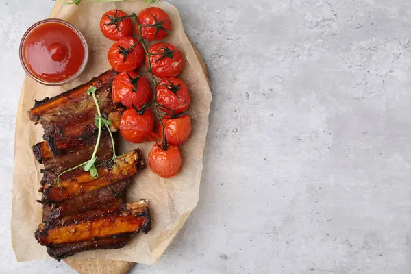 Kızarmış biftek pirzolası, mikroyeşillikler, domatesler ve sosla gri desenli masa, üst manzara. Metin için boşluk