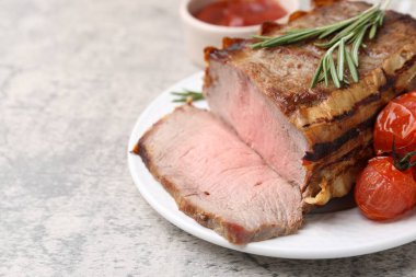 Lezzetli pişmiş et, domates, biberiye ve sos gri masada, yakın plan. Metin için boşluk